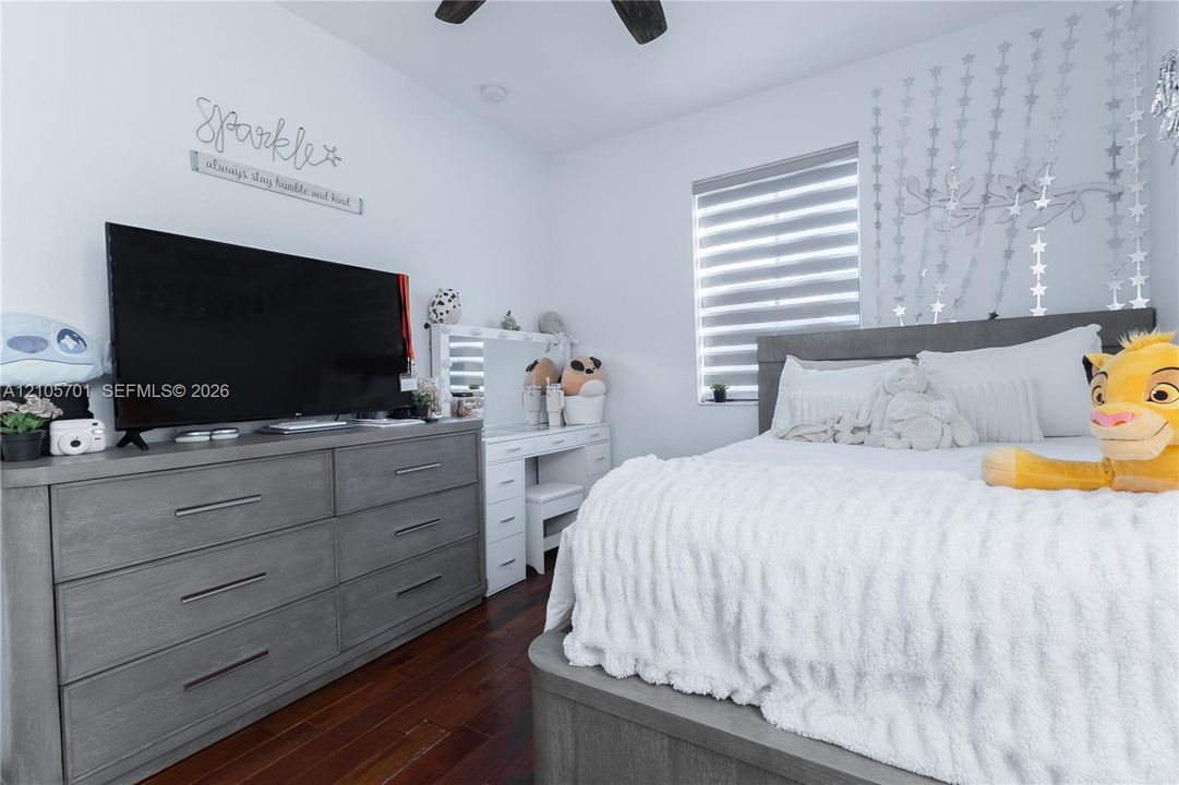 Room featuring wood-finish flooring, a ceiling fan, and horizontal window shades
