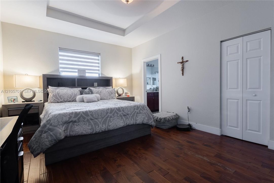 Room featuring tray ceilings, wood-finish flooring, and dual-panel closet doors