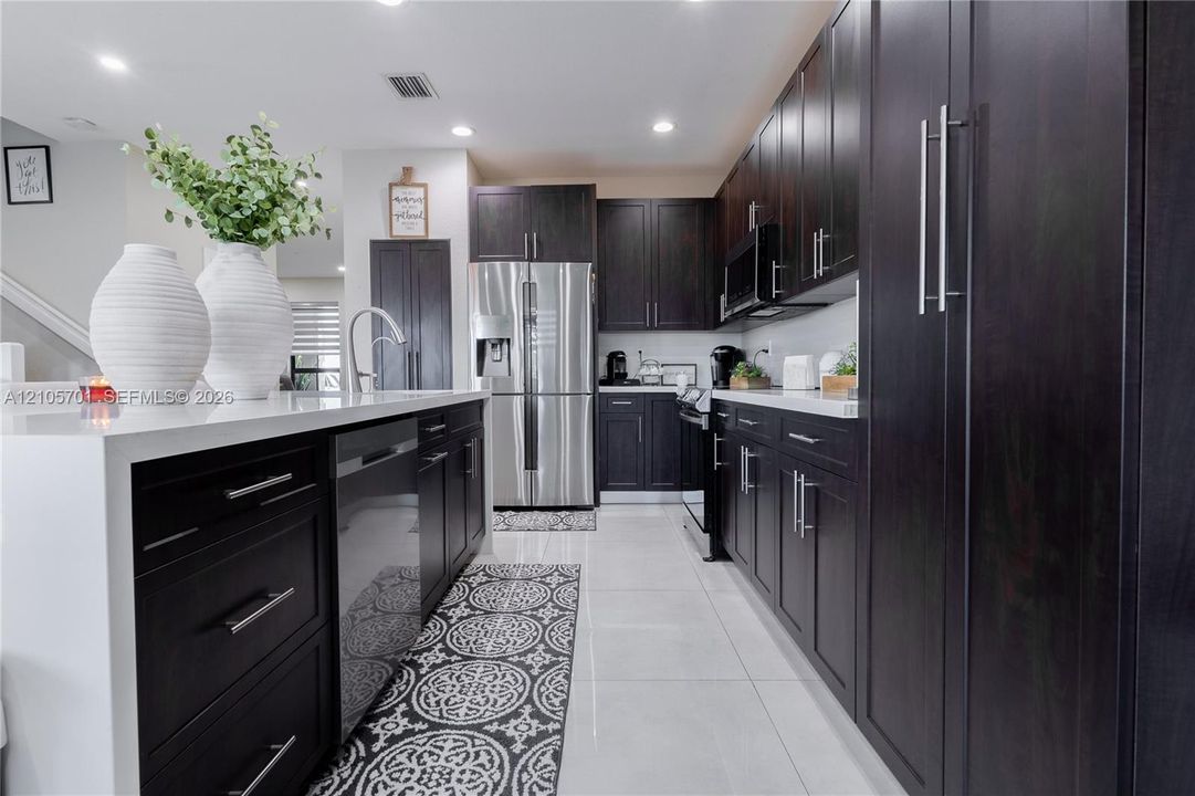 Kitchen featuring dark wood cabinetry, white countertops, stainless steel appliances, recessed lighting, and tile flooring