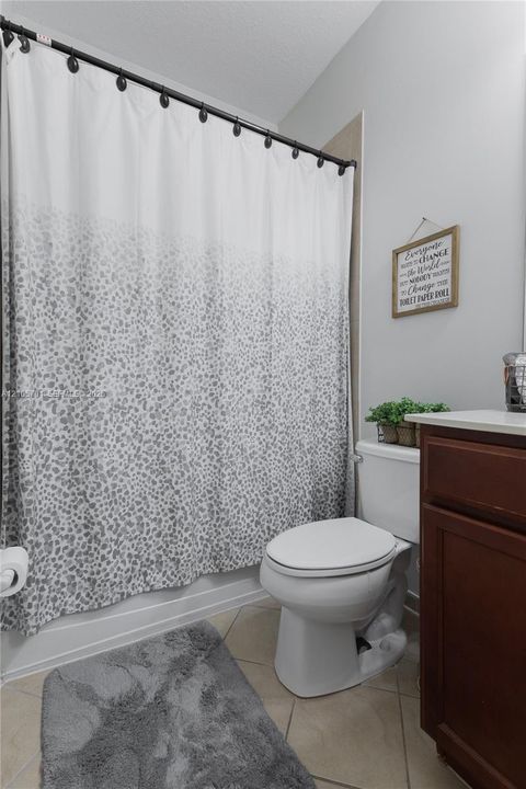 Bathroom featuring dark wood-finish cabinetry, a light-toned countertop, and tile flooring