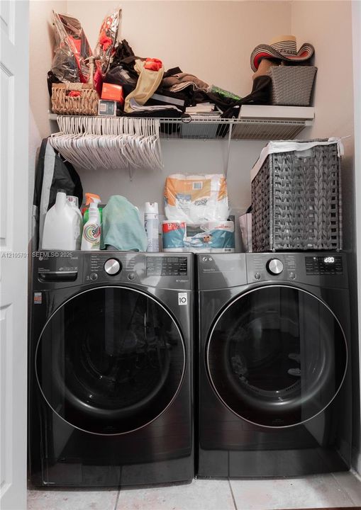 Laundry closet featuring side-by-side charcoal-finish front-load washer and dryer with wire shelving