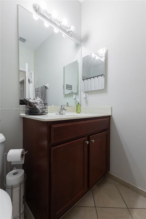 Wood-finish vanity cabinet, solid-surface countertop, full-width mirror, and multi-bulb light fixture