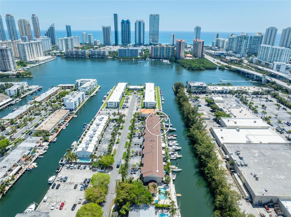 Aerial perspective featuring a waterfront building with dedicated boat slips, direct waterway access, and a surface parking lot