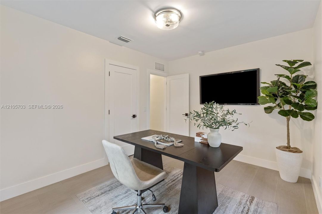 Neutral-toned interior featuring wood-finish flooring, solid-core doors with matte black hardware, and a flush-mount drum ceiling light