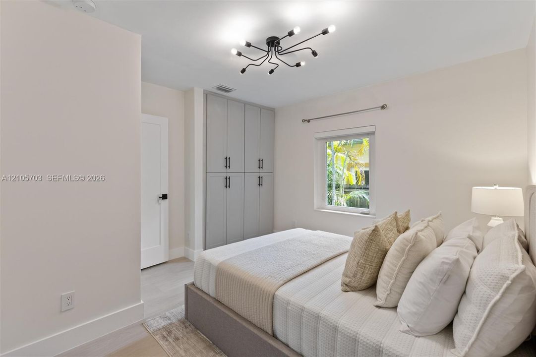 Multi-light spider chandelier, built-in floor-to-ceiling cabinetry with matte black hardware, and wood-finish flooring