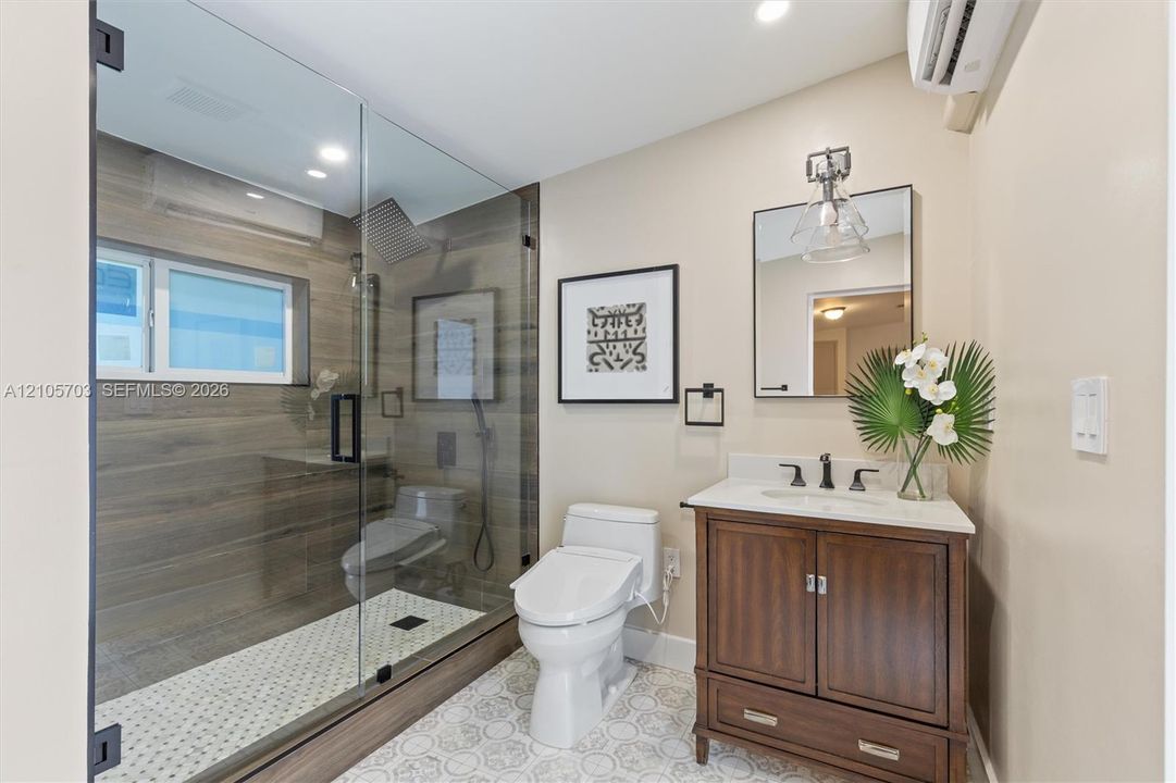 Walk-in shower with wood-finish tile surround, frameless glass enclosure, and rainfall showerhead