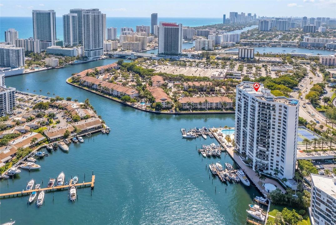 High-rise building situated on a waterway, featuring private boat slips, an outdoor swimming pool, and a tennis court