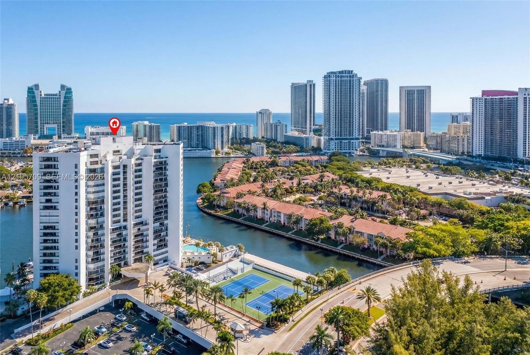 High-rise residential building featuring an on-site swimming pool, tennis courts, and waterfront positioning