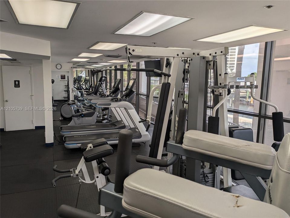 Fitness facility featuring rubberized flooring, expansive floor-to-ceiling windows, and recessed panel lighting