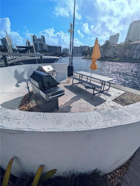 Waterfront patio featuring a curved masonry wall, tile pavers, and direct bulkhead access
