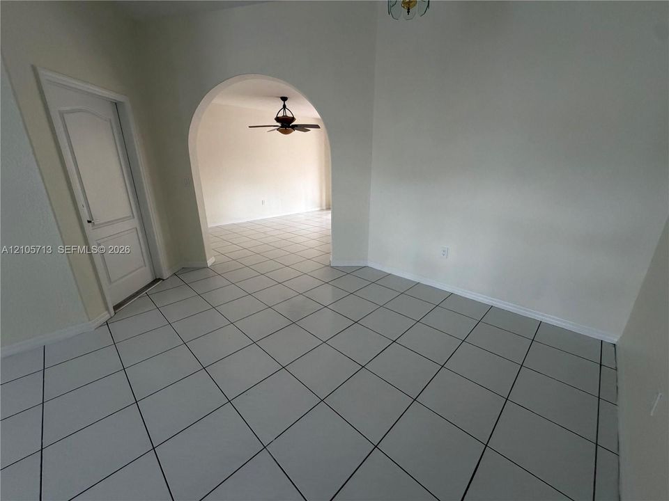Ceramic tile flooring, arched entryway, and six-panel interior door