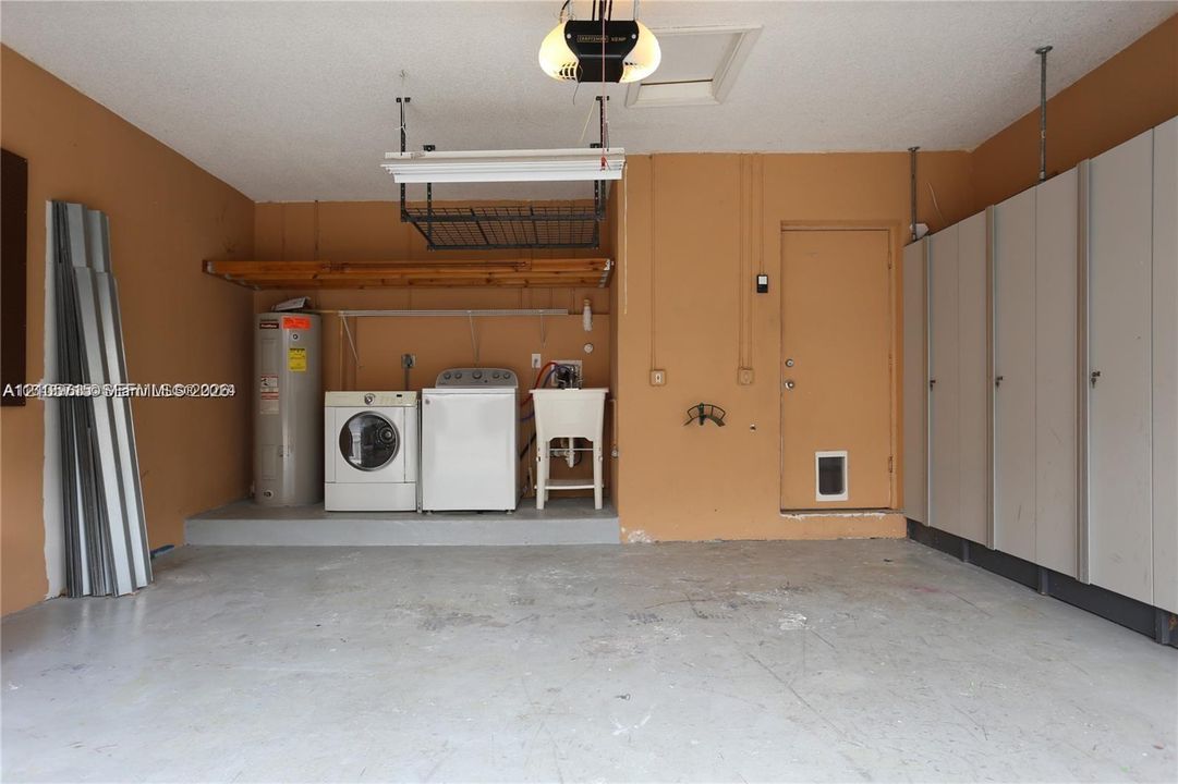 Garage space featuring built-in floor-to-ceiling cabinetry, overhead ceiling storage rack, utility sink, and wall-mounted shelving