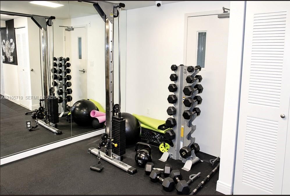 Fitness space featuring floor-to-ceiling wall mirrors, durable rubberized flooring, and dual white louvered-panel doors