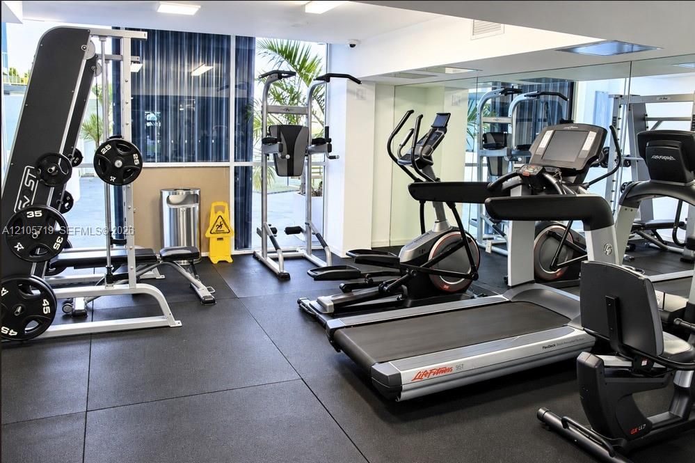 Fitness center featuring rubberized flooring, mirrored wall, and floor-to-ceiling windows