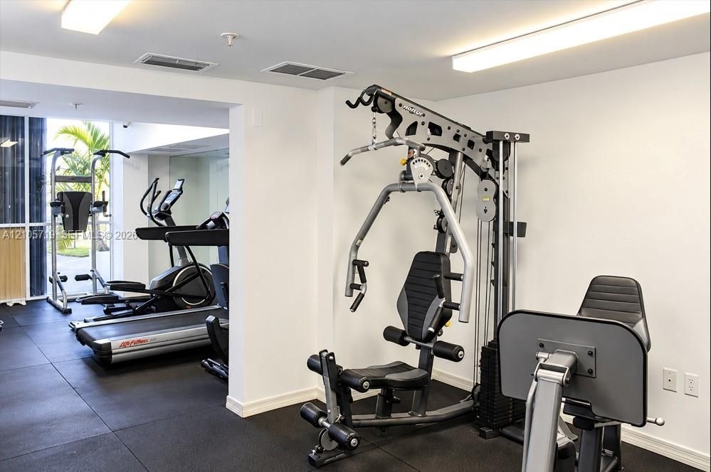 Fitness room featuring rubberized flooring, floor-to-ceiling mirror, and ceiling-mounted linear lighting