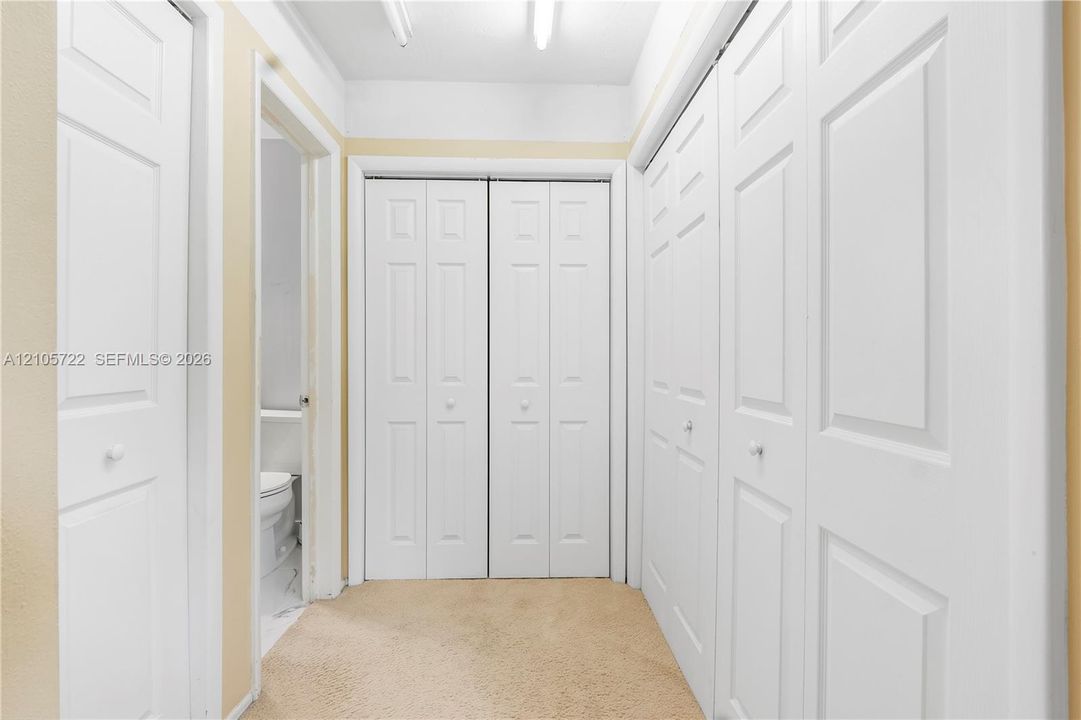 Hallway featuring multiple bi-fold doors, six-panel interior doors, and carpeted flooring