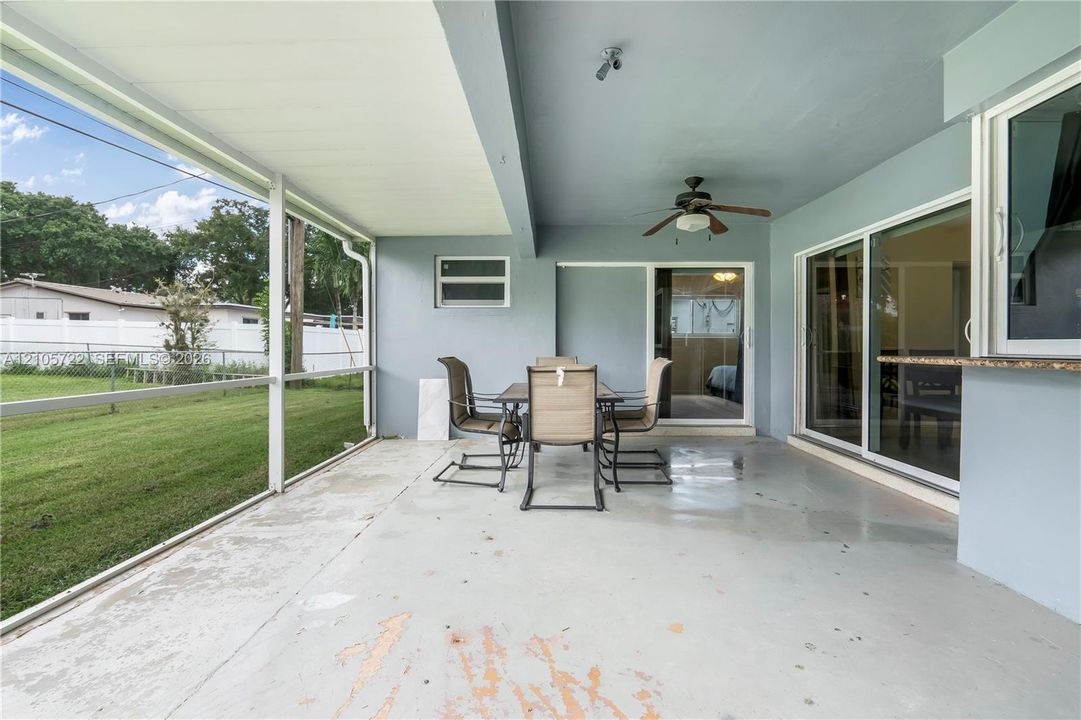 Screened-in patio featuring a concrete floor, ceiling fan, and sliding glass door entry