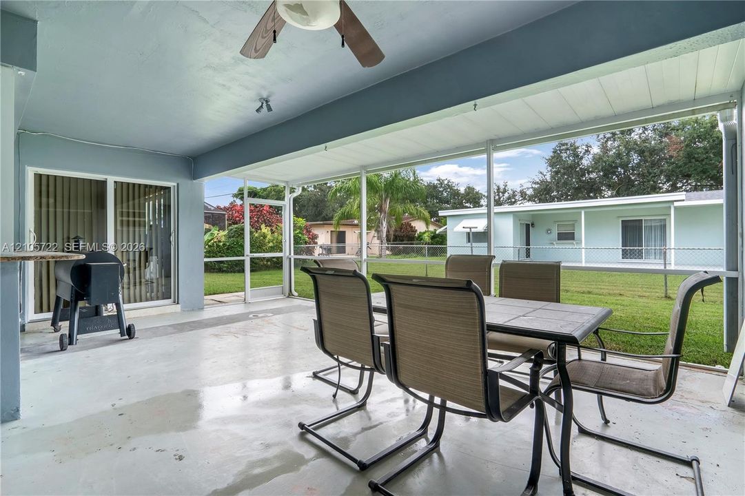Screened-in patio featuring a concrete floor, ceiling fan, and sliding glass door entry