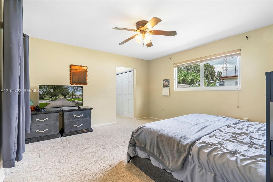 Neutral-toned interior featuring carpeted flooring, a ceiling fan with integrated lighting, and a window with roller shade