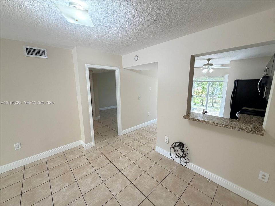 Neutral-toned interior featuring ceramic tile flooring, a stone-surface pass-through counter, and a flush-mount ceiling light fixture