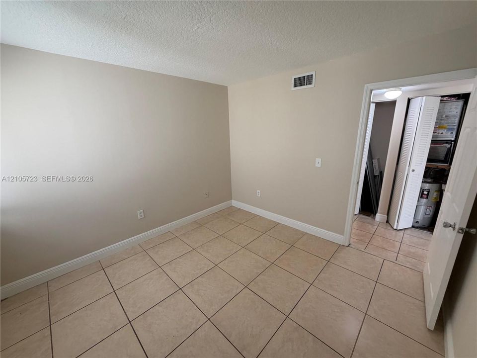 Neutral-toned interior space featuring ceramic tile flooring, a six-panel interior door, and a folding-door closet