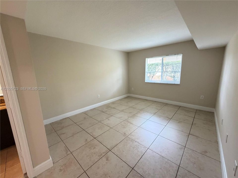 Neutral-toned interior space featuring light-colored square tile flooring, smooth walls, and a single-pane window