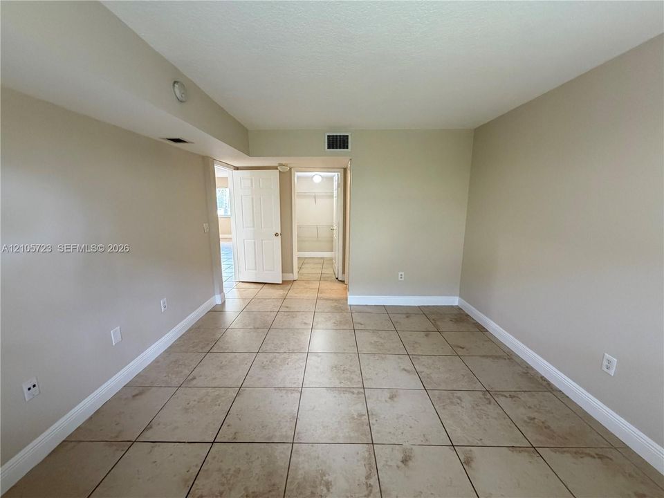 Neutral-toned interior space featuring tile flooring and a walk-in closet with built-in shelving