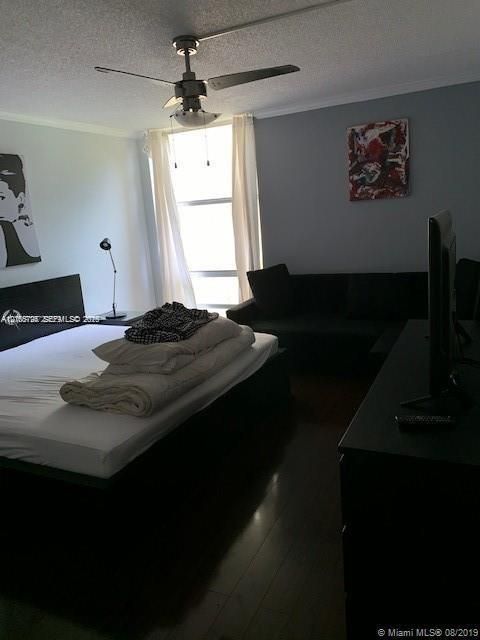 Interior space featuring wood-finish flooring, floor-to-ceiling windows, and a ceiling-mounted light fixture with integrated fan