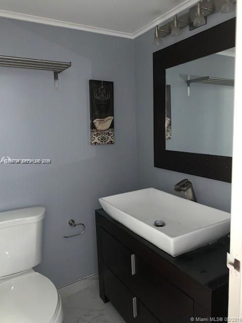 Dark wood-finish vanity featuring a white rectangular vessel sink, mounted mirror with a matching dark frame, and multi-bulb light fixture