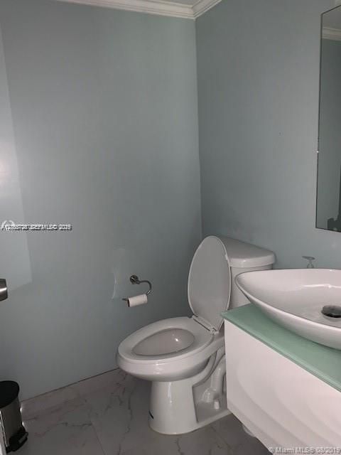Wall-mounted vanity with a frosted glass countertop and white vessel sink, paired with a white two-piece toilet and large-format tile flooring