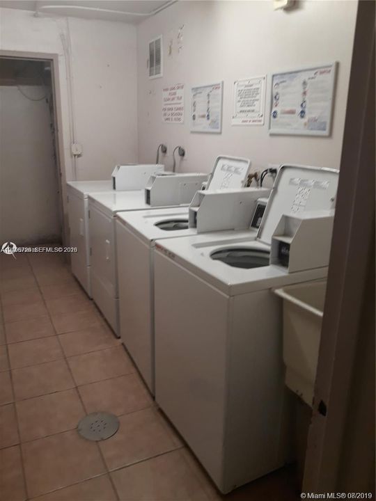 Laundry area featuring multiple top-loading washing machines and ceramic tile flooring