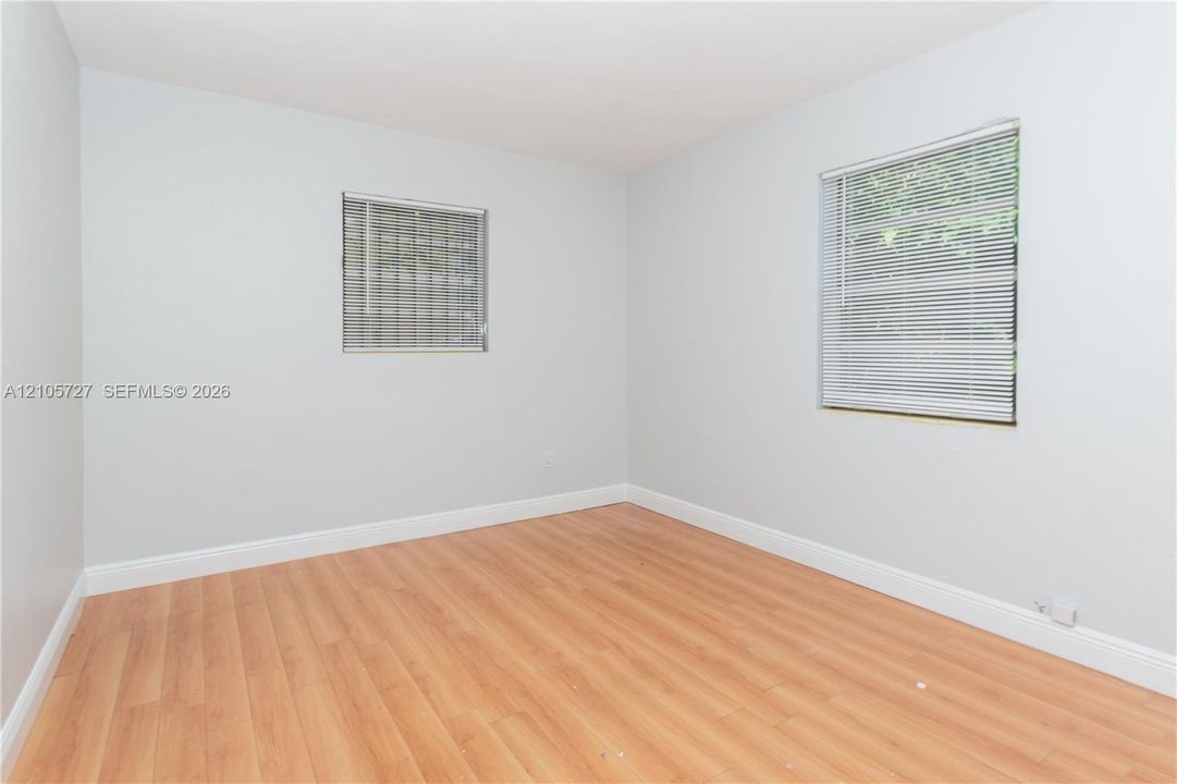 Interior space featuring wood-finish flooring, light-toned wall paint, and two windows with horizontal blinds