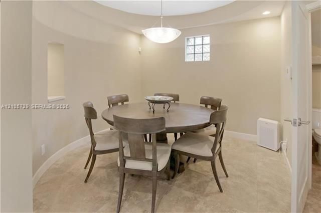 Circular room featuring stone-finish flooring, a recessed wall niche, a square glass-block window, and a central pendant light fixture