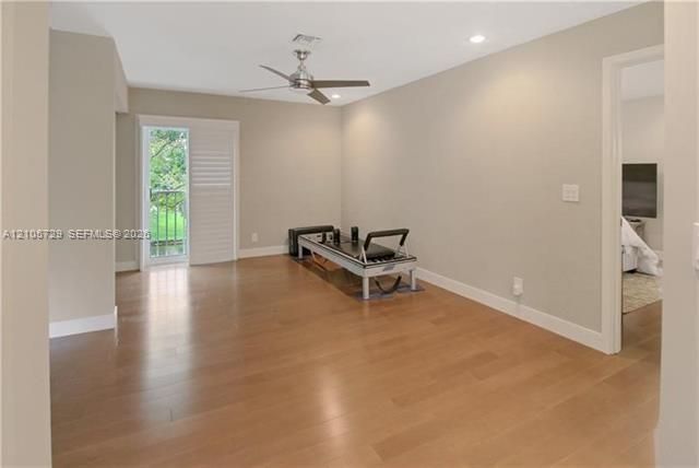 Open legal 4th bedroom, used as family space. Can easily be closed. Room featuring wood-finish flooring, neutral wall paint, recessed lighting, a brushed-metal ceiling fan, and glass-paneled sliding door with louvered shutters