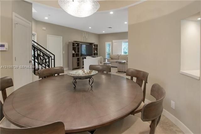 Circular dining area featuring a tray ceiling, recessed lighting, a large pendant light fixture, and tile flooring