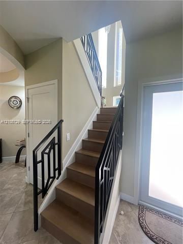 Staircase featuring wood-finish treads and custom black geometric metal railings, illuminated by tall vertical windows