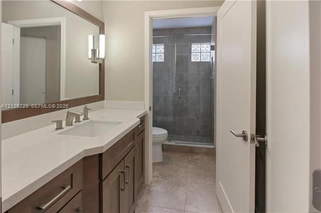 Bathroom featuring a vanity with white countertop, integrated sink, framed mirror, and wood-finish cabinetry