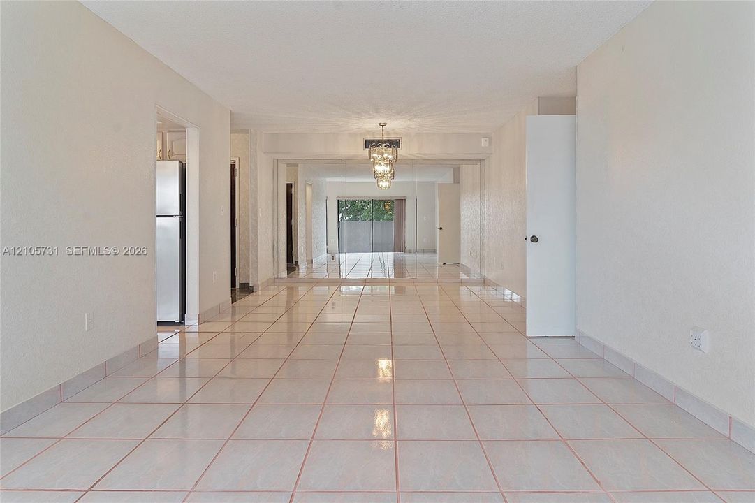 Neutral tile flooring, expansive mirrored wall panels, and a tiered crystal chandelier