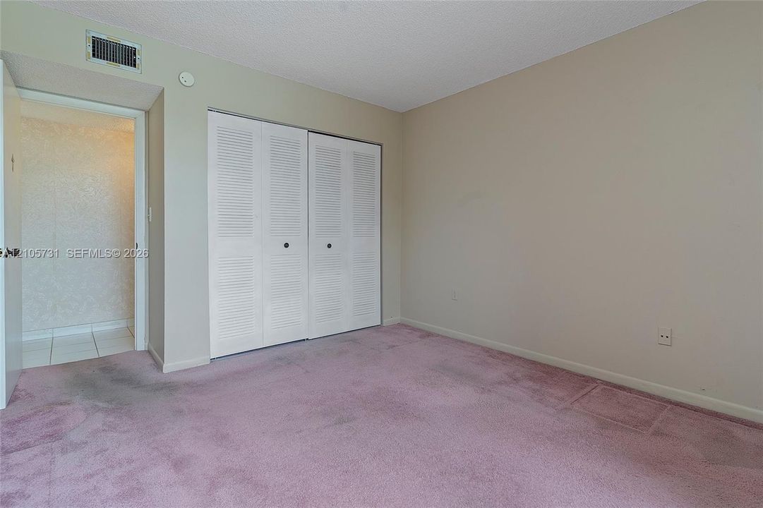 Interior space featuring carpeted flooring, white louvered-style bi-fold closet doors, and neutral wall paint