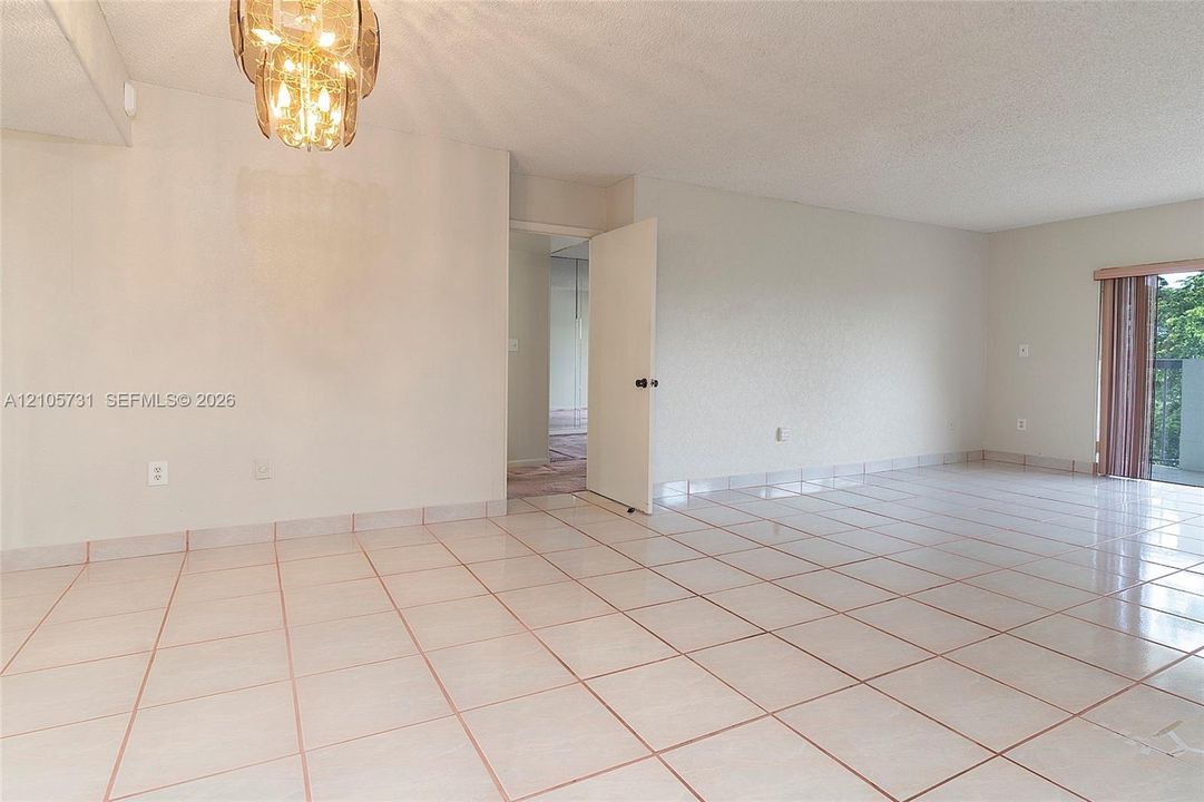Large format tile flooring, metallic multi-light chandelier, and full-height glass door panel