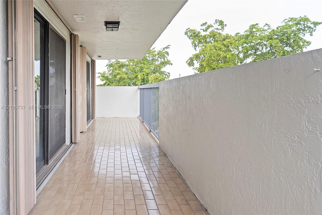 Covered balcony featuring tile flooring, textured wall finishes, and metal railing