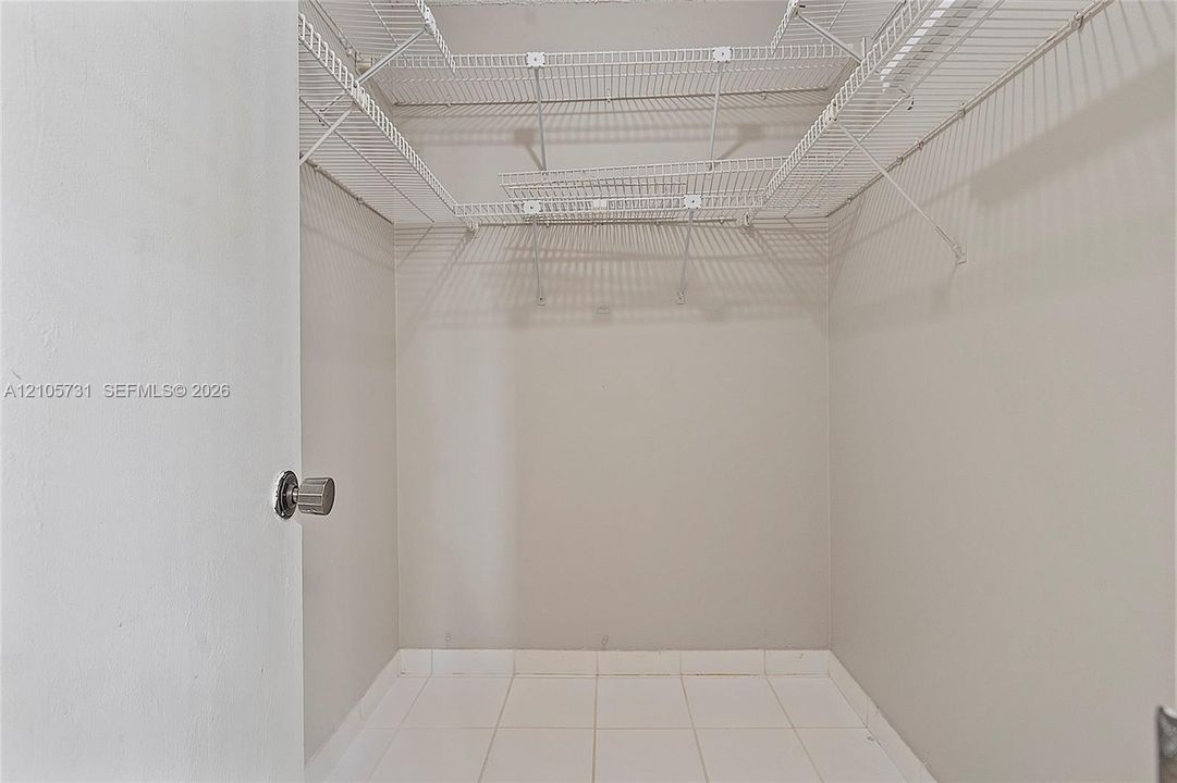 Storage area featuring white wire shelving and tile flooring