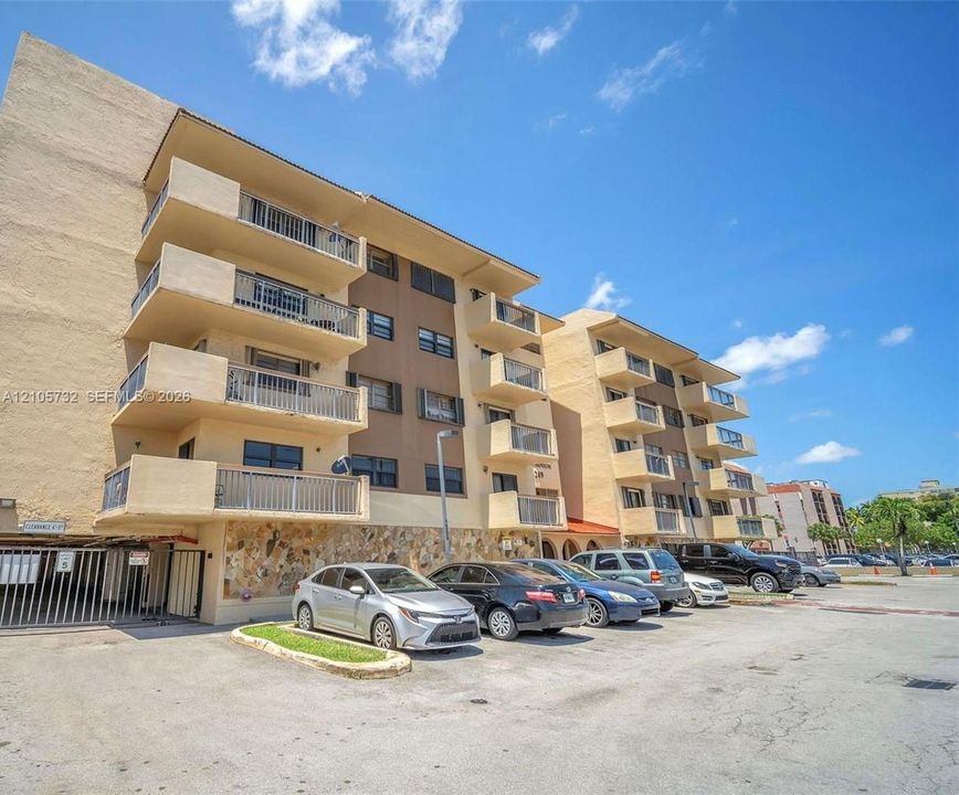 Multi-story residential building featuring private balconies, natural stone cladding at the ground level, and gated ground-level parking