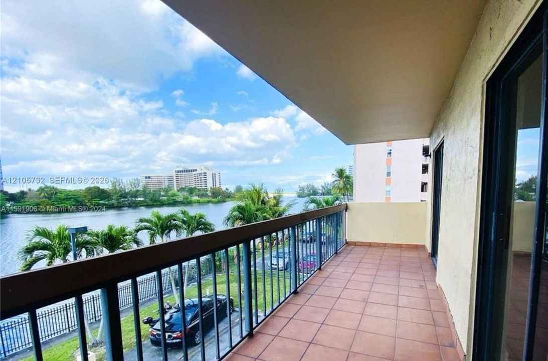 Covered balcony featuring tile flooring and metal railings, overlooking the waterfront