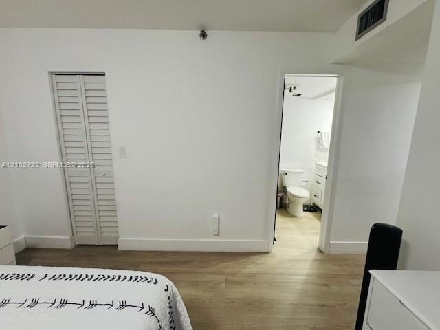 Room featuring wood-finish flooring, white walls, and a bi-fold closet door