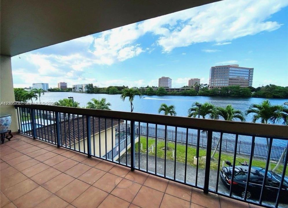 Covered terrace with terracotta-style tile flooring and a dark metal railing overlooking a waterway