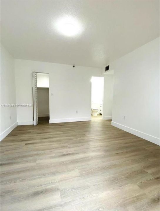 Interior space featuring wood-finish flooring, white walls, and a recessed closet with bi-fold doors
