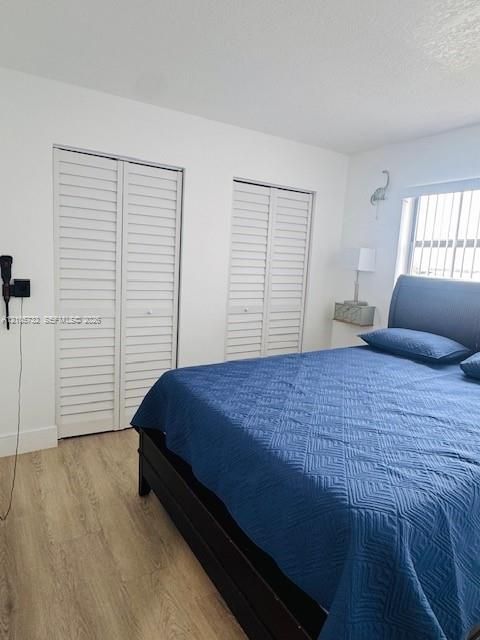 Neutral wall tones with wood-finish flooring, dual bi-fold louvered closet doors, and wall-mounted lighting fixture