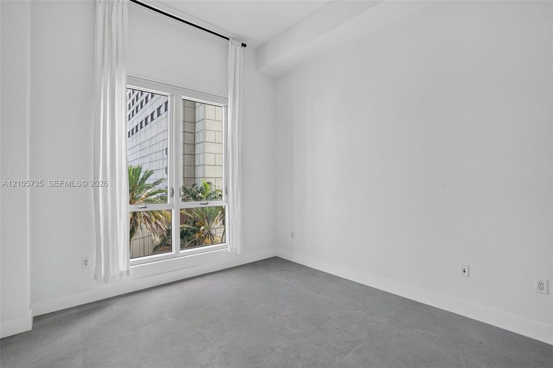 High ceilings featuring a large window with neutral finishes and grey flooring
