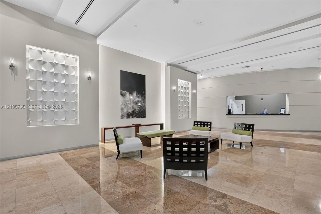 Grand lobby featuring polished stone flooring, recessed architectural wall niches with textured dimensional tile, custom crown molding, and recessed ceiling lighting